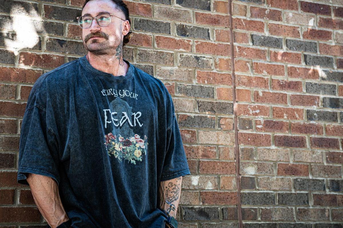 Athlete leaning on a brick wall in a washed ERND Bury Your Fear tee