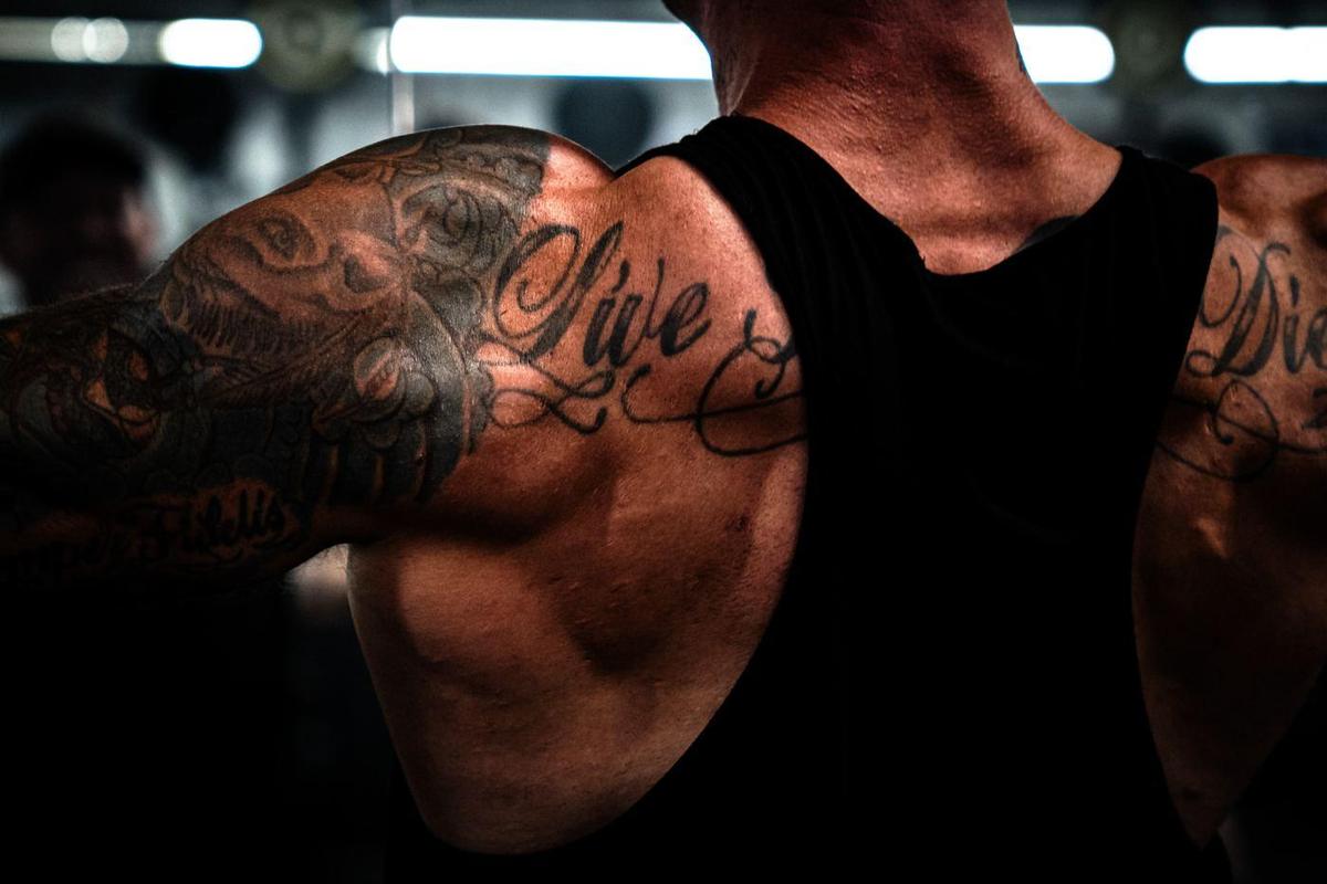 Script tattoo across a lifter's back and shoulders