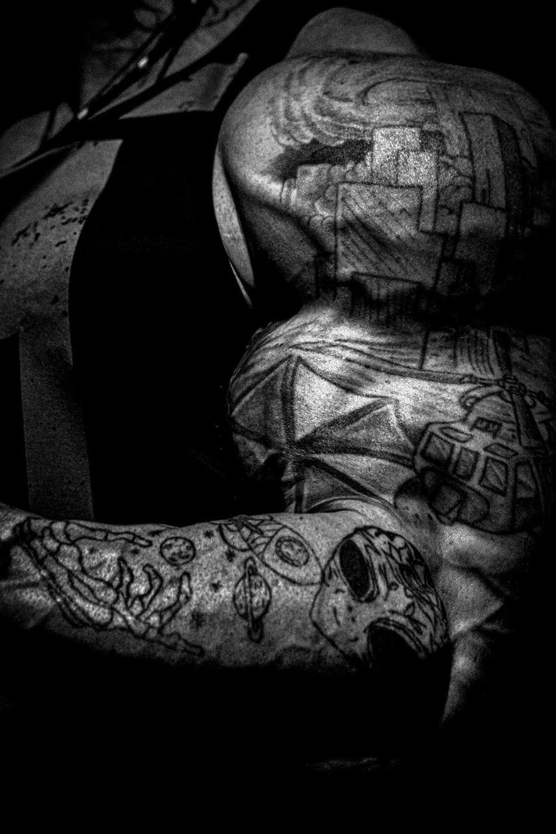 Black and white close-up of a fully tattooed arm and shoulder