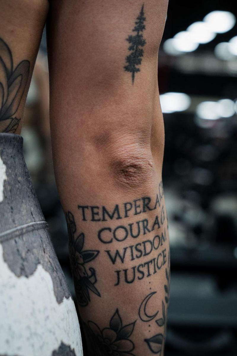Close-up of a forearm tattoo reading temperance, courage, wisdom, justice
