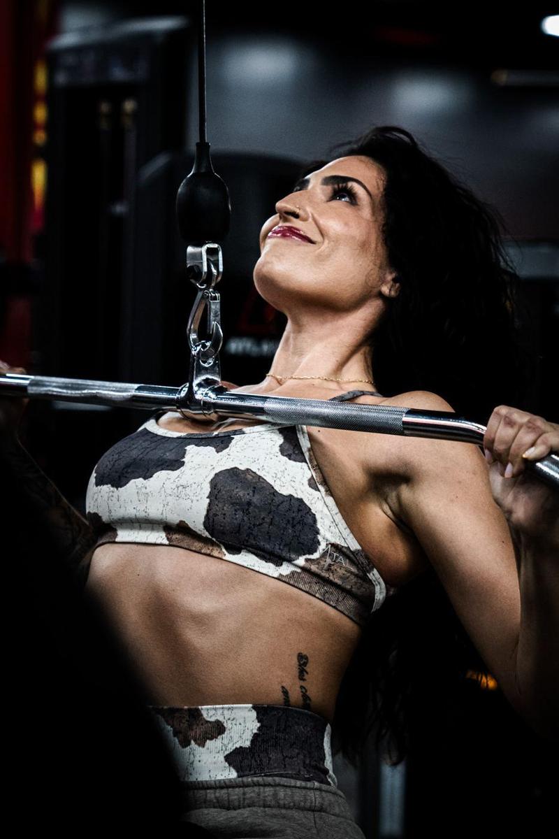 Female athlete smiling mid-rep on a lat pulldown